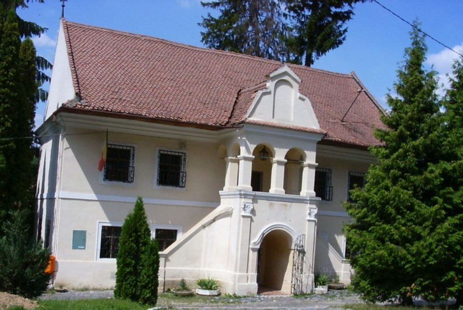 Prima Scoala Romaneasca se află în interiorul curții Bisericii Sfântul Nicolae din cartierul istoric Șcheii Brașovului.